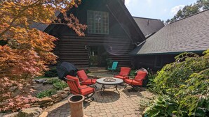 A log cabin with a patio area featuring red chairs, a round table, and a large terracotta vase. - special offers: 20% off all winter bookings,10% discount for early reservations. (Baltimore)