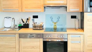 A modern kitchen with wooden cabinets, stainless steel appliances, a sink, and a decorative sign with a deer. - Stunning Apartment in Mettmann With Wifi (Mettmann)