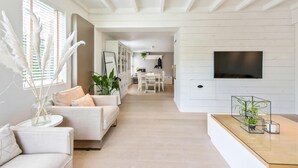 Un vaste espace de vie comprenant un canapé, une table basse et un téléviseur fixé au mur.