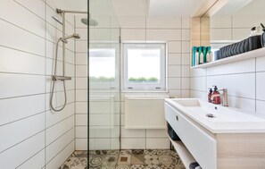 Une salle de bain moderne équipée d’une douche, d’une fenêtre et d’un lavabo avec des articles de toilette.