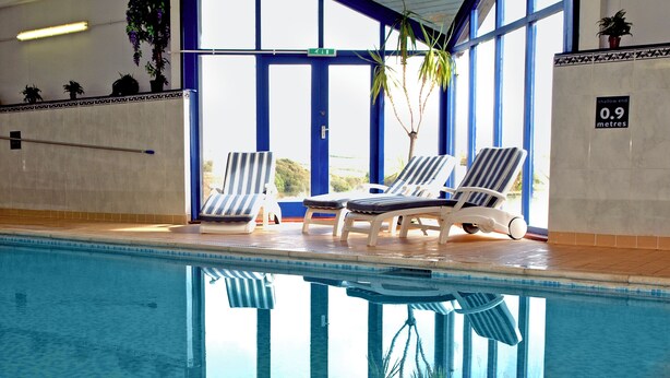 An indoor swimming pool with lounge chairs and potted plants. - The Corn Store - UK6716 (Lydstep, near Tenby)