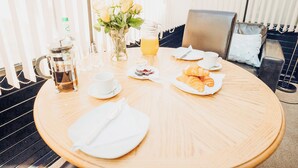 A breakfast table with a coffee pot, a pitcher of orange juice, croissants, and a vase with flowers. - The Corn Store - UK6716 (Lydstep, near Tenby)