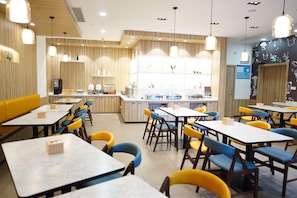 A restaurant with multiple tables and chairs, a counter with a display, and a wall with a pattern.