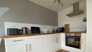 A modern kitchen with white cabinets, a wooden countertop, a built-in oven, and a microwave. - Perfect for beach & nature reserve walks all year round (Pagham)