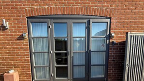 A set of double doors with a no smoking sign, a small outdoor unit, and a metal grate at the entrance. - Perfect for beach & nature reserve walks all year round (Pagham)