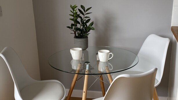 A round glass table with two white chairs, a potted plant, and two white cups. - Perfect for beach & nature reserve walks all year round (Pagham)
