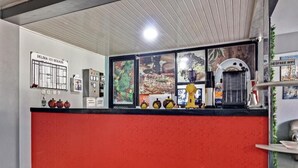 Ein Empfangsschalter mit roter Theke, einer Uhr und einer Wandtafel mit Speisekarte.