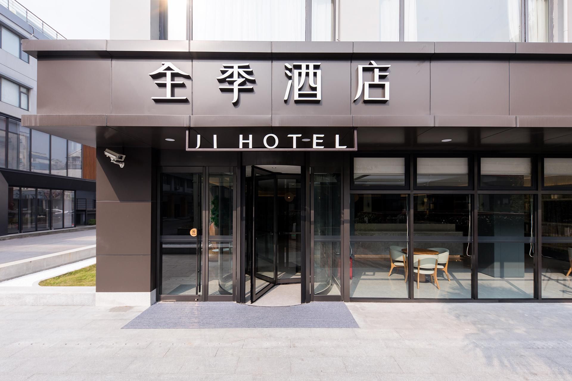 A hotel entrance with glass doors, a security camera, and a seating area visible through the glass.
