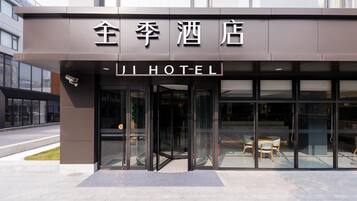 A hotel entrance with glass doors, a security camera, and a seating area visible through the glass.