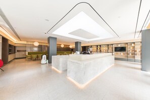 A modern hotel lobby with a central island, seating area, and a large TV screen. - Ji Hotel Shanghai Longbai Xincun Metro Station (Shanghai)