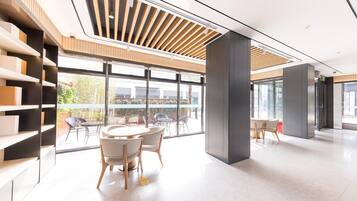 Ein modernes Interieur mit einer zentralen Sitzecke, großen Fenstern und einer Decke aus Holzleisten.