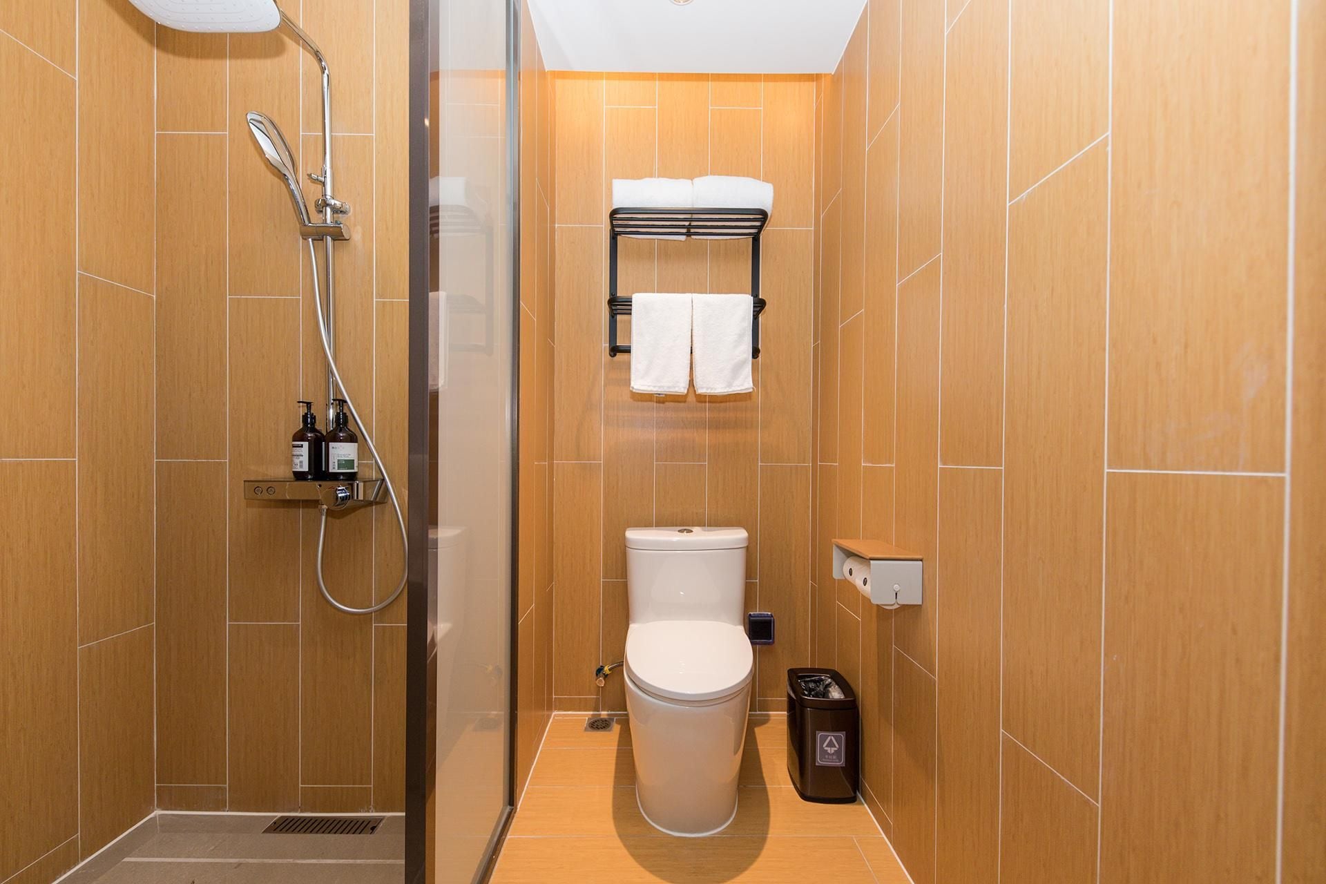 Et lille, moderne badeværelse med bruser, toilet og håndklædestang.