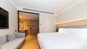 Ein Hotelzimmer mit Bett, Sofa, Badezimmer mit Spiegel und Fernseher.