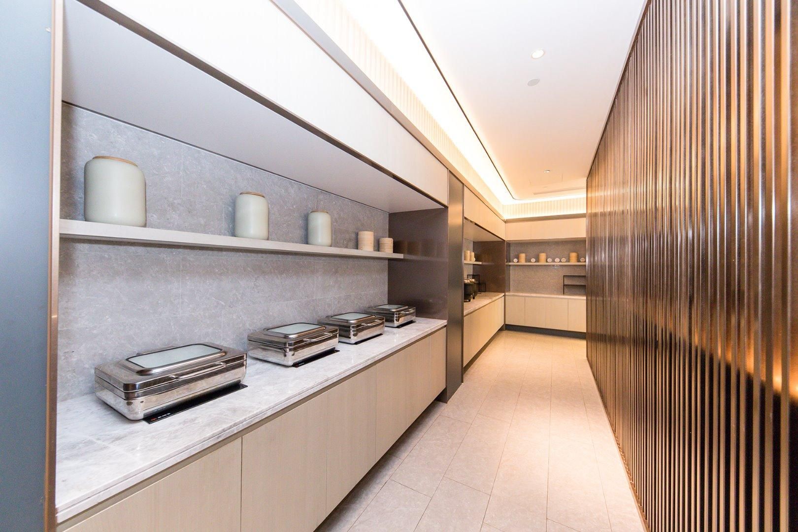 A modern kitchen with built-in appliances, a marble countertop, and a wooden panel wall.