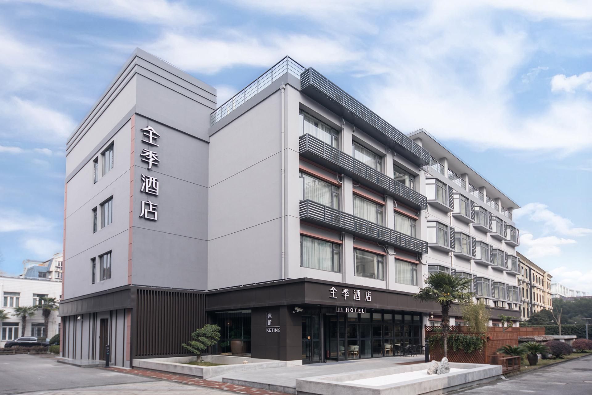 A modern hotel building with a prominent entrance, multiple balconies, and a clear sky.