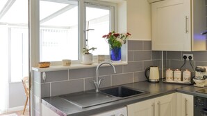 Een kleine keuken met een inbouw wasmachine, een spoelbak en een raam met uitzicht.