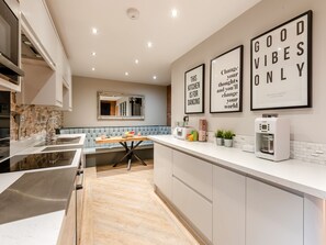 Een moderne keuken met een centraal eiland, een steen rugpaneel en een zithoek met een bank.