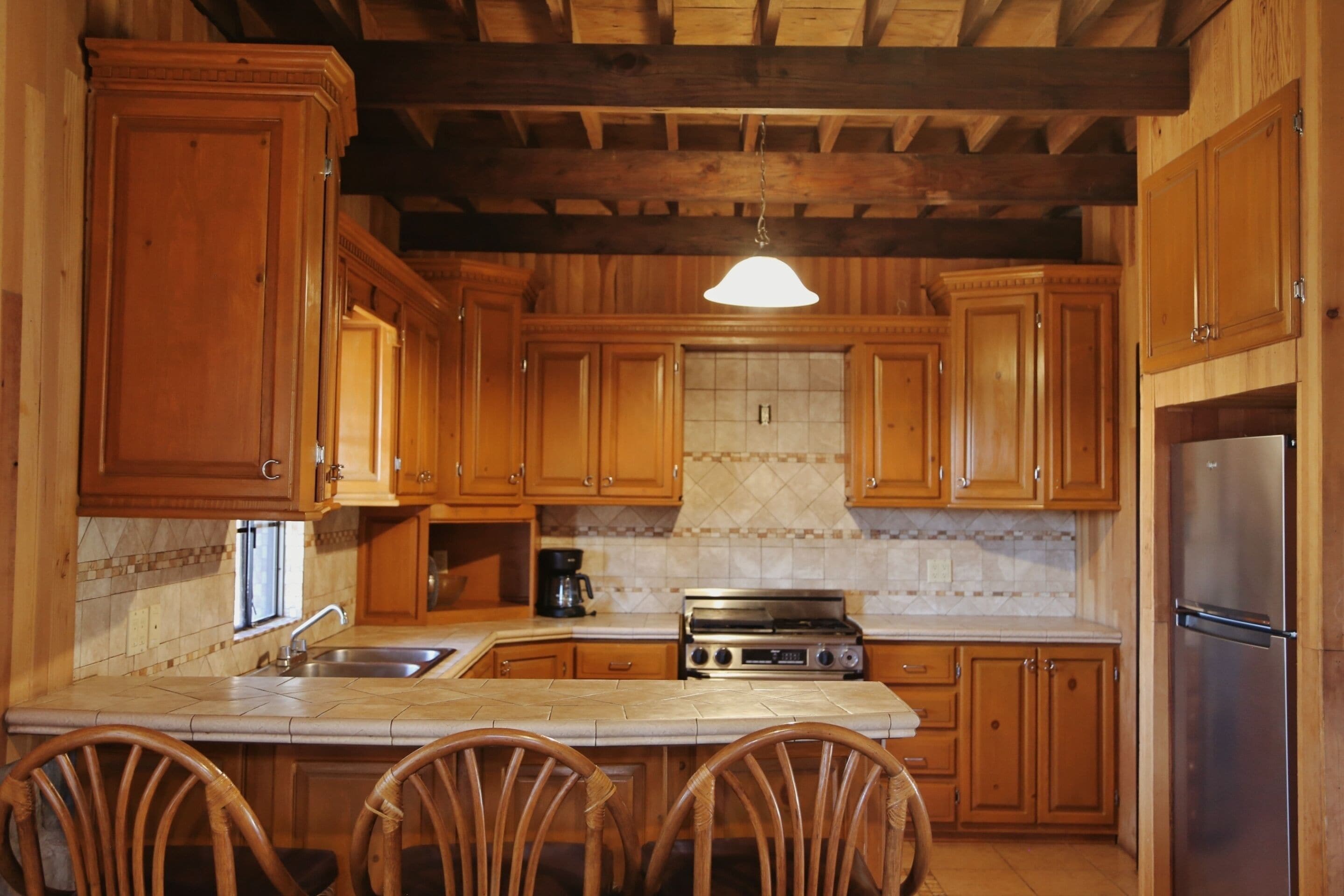 Una cocina con armarios de madera, estufa de acero inoxidable y refrigerador.