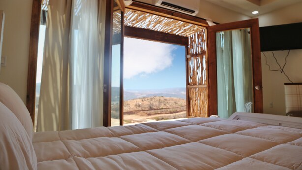 Un dormitorio con una cama grande, vistas al exterior y un equipo de aire acondicionado en la pared.