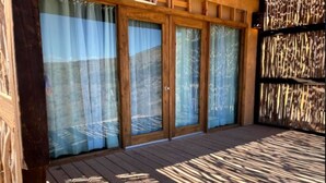 Una terraza de madera con puertas de vidrio y vista al exterior.