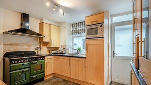 A kitchen with wooden cabinets, a stove, a microwave, and a window.