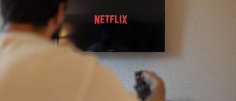 A person sitting in front of a television displaying the Netflix logo.
