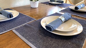 Een eettafel gedekt met borden, servetten en tafelmatten.