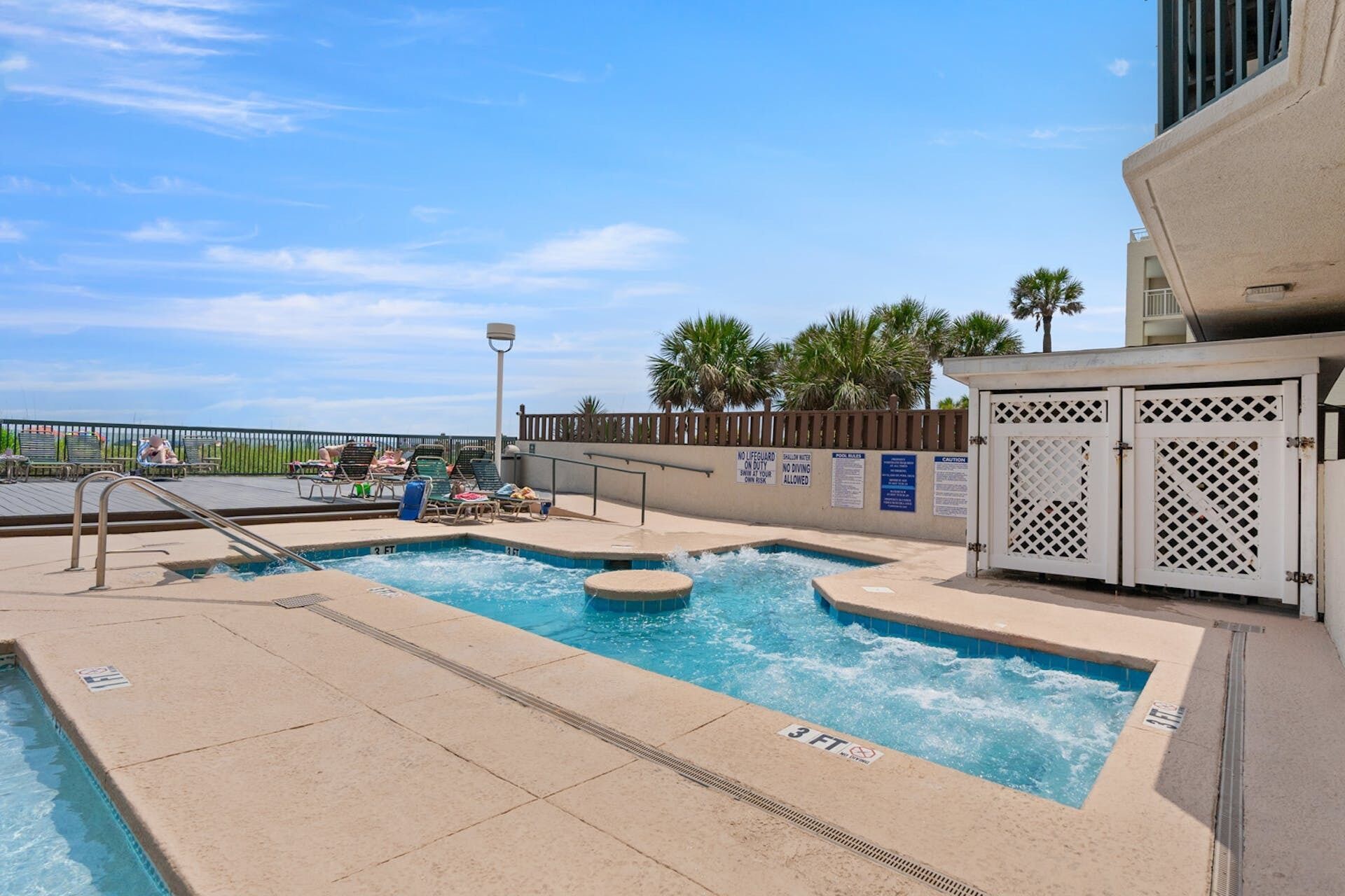 A pool area with lounge chairs and a lifeguard station.