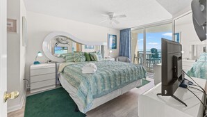A bedroom with a bed, a desk with a computer, a ceiling fan, and a large window with a view. - 4-bedroom, 3-bathroom, family-friendly oceanfront condo, 9th floor views | Windy Hill Dunes - 906 (North Myrtle Beach)