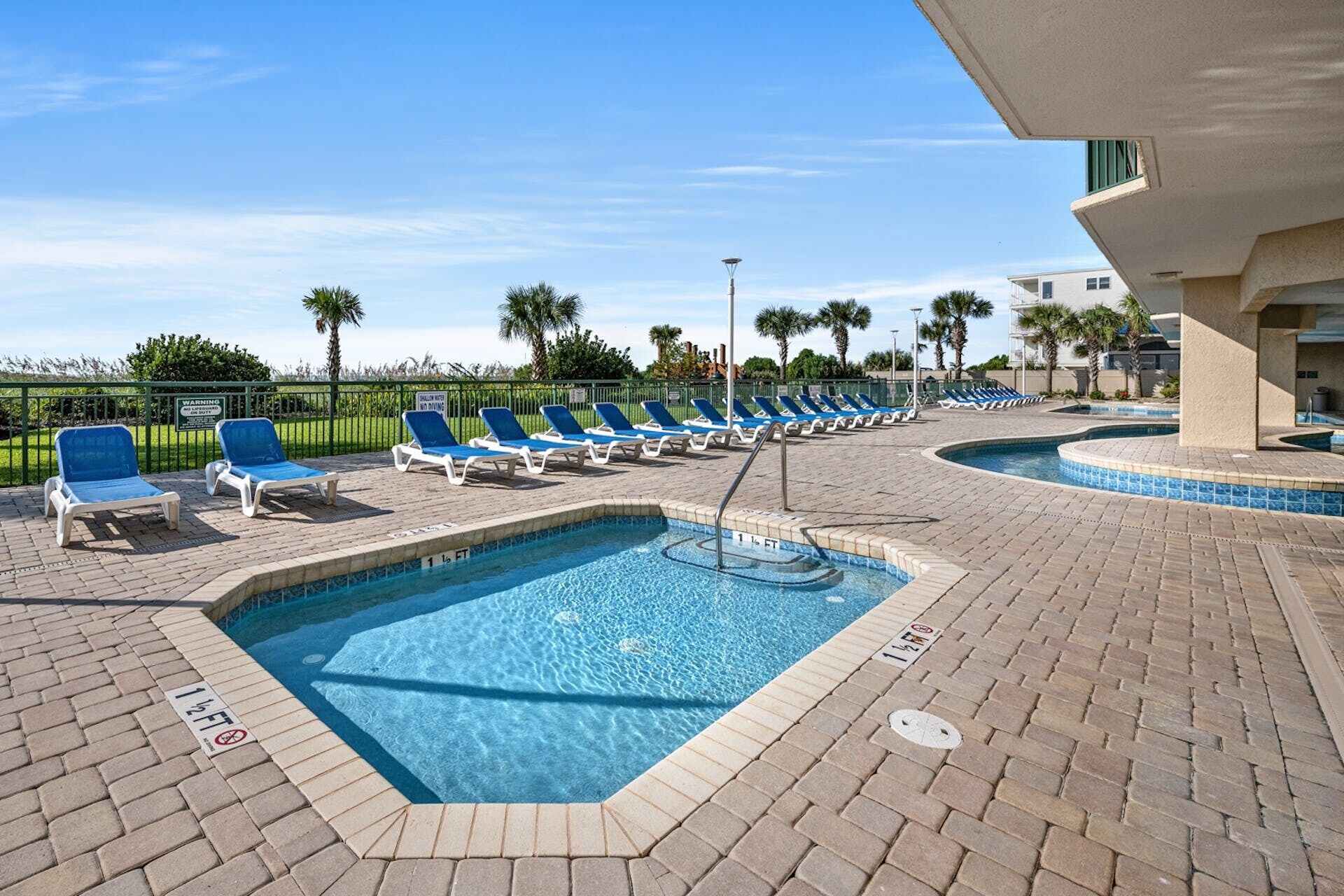 A pool area with lounge chairs and a sign indicating a 12 ft depth.
