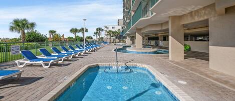 A pool area with lounge chairs and a shallow water sign.