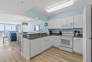 A modern kitchen with white cabinets, a granite countertop, and stainless steel appliances. - Lovely 4-bedroom oceanfront condo at the AshWorth  | AshWorth - 605 (North Myrtle Beach)