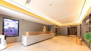 Un espace d’accueil moderne, doté d’un comptoir de réception, d’un grand écran numérique et d’un design épuré et minimaliste.