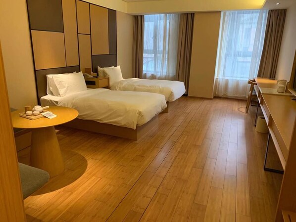 Quarto de hotel com duas camas, uma mesa redonda com um tabuleiro de chá e uma escrivaninha com uma cadeira.
