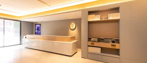 A modern reception area with a reception desk, a digital screen, and a wall-mounted clock.