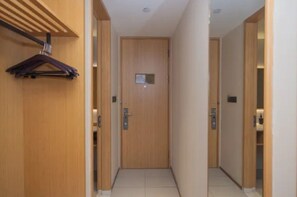 Un pasillo con puertas de madera, un perchero y un interruptor de luz en la pared.