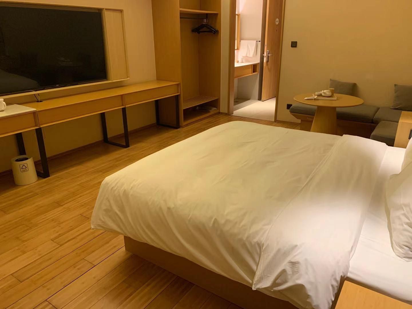 Une chambre d’hôtel avec un lit, un bureau, une chaise, une petite table et un téléviseur.