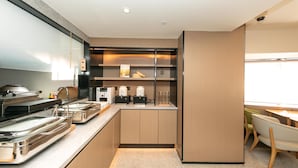 Une cuisine moderne dotée d’appareils électroménagers en acier inoxydable, de meubles en bois et d’un bar pour prendre le petit-déjeuner.