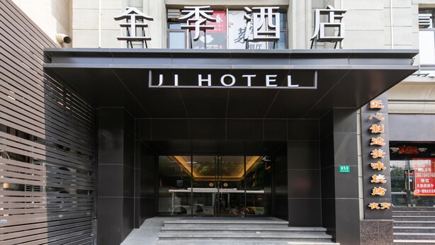 L’entrée de l’hôtel Ji se distingue par sa façade moderne, ses portes vitrées et un escalier bien visible qui mène à l’entrée.