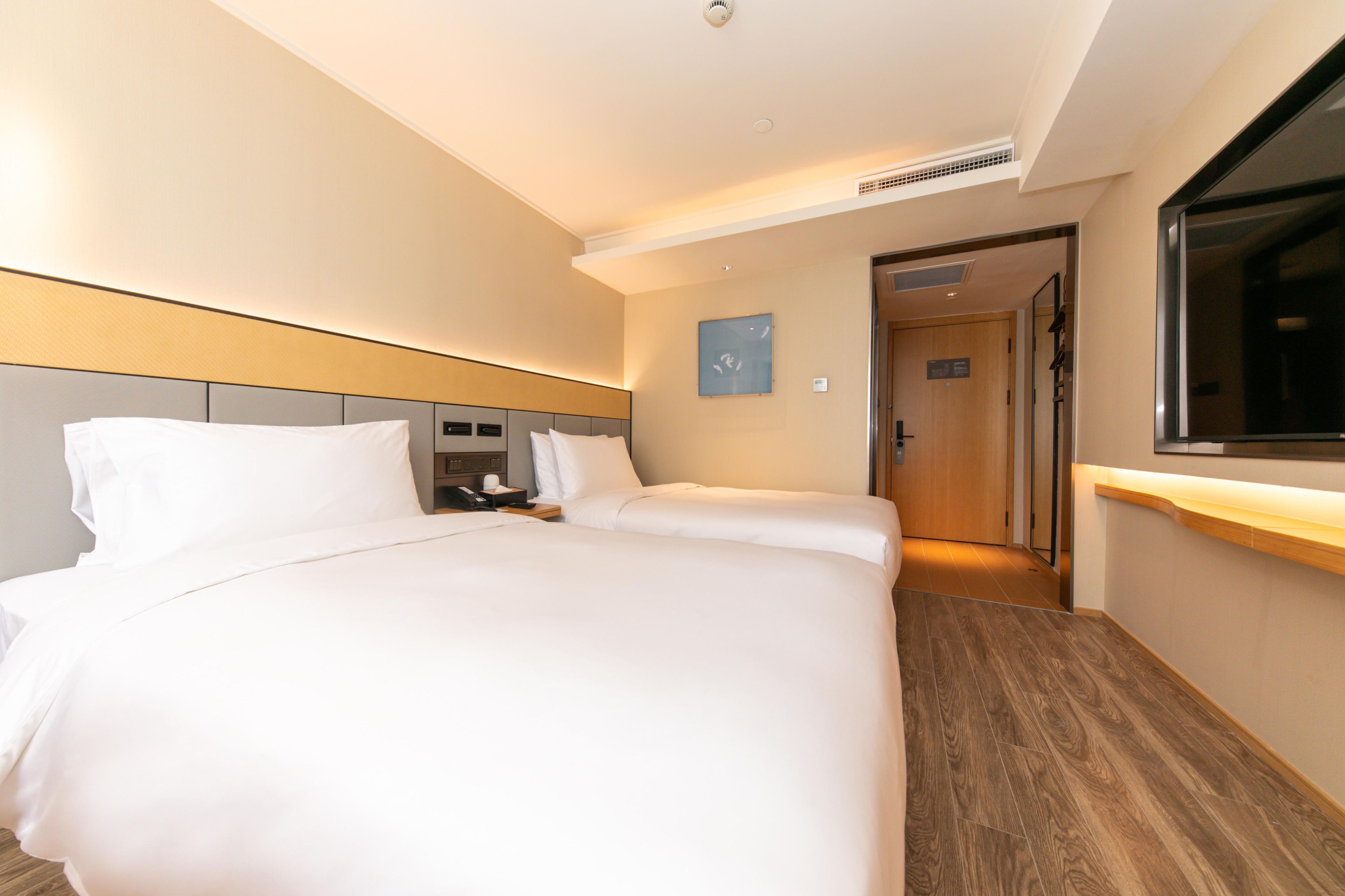 Une chambre d’hôtel avec un grand lit, une table de chevet, une télévision et un plancher en bois.
