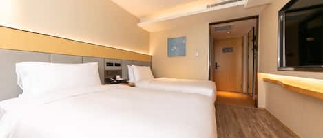 A hotel room with a large bed, a bedside table, a TV, and a wooden floor.