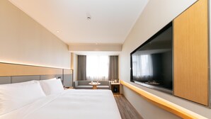 Une chambre d’hôtel avec un grand lit, un canapé, une télévision et une fenêtre.
