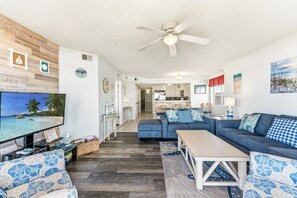 A living room with a TV, sofas, a coffee table, and a ceiling fan.