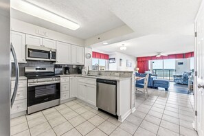 A modern kitchen with stainless steel appliances, a dining area with a view, and a living room with a balcony.