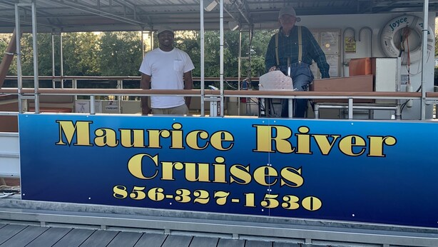 A boat with a sign reading "Maurice River Cruises" and a contact number.
