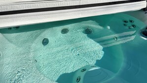 A hot tub with clear water and visible bubbles, surrounded by a white and black striped cover.