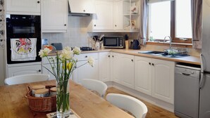Una cocina moderna con armarios blancos, un microondas, un horno y un lavavajillas.