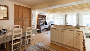 A spacious kitchen with wooden cabinets, a dining area with chairs, and a large window providing natural light. - 4 bedroom accommodation in Church/Market (Church/Market)