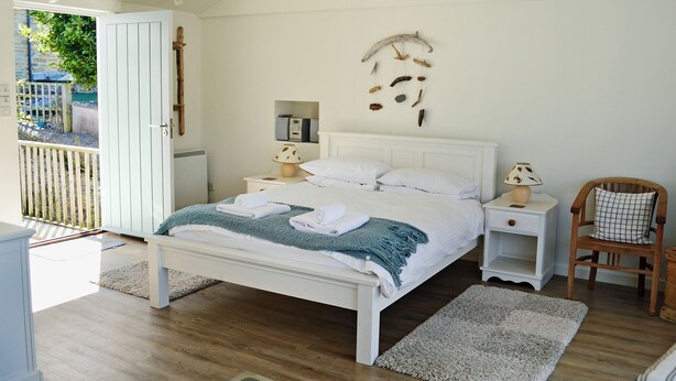 A neatly arranged bedroom with a bed, bedside tables, a chair, and a view of the outside. - 4 bedroom accommodation in Church/Market (Church/Market)