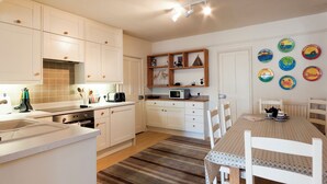 A compact kitchen with white cabinets, a microwave, and a toaster. There is a dining table with chairs and a striped rug. - 4 bedroom accommodation in Church/Market (Church/Market)